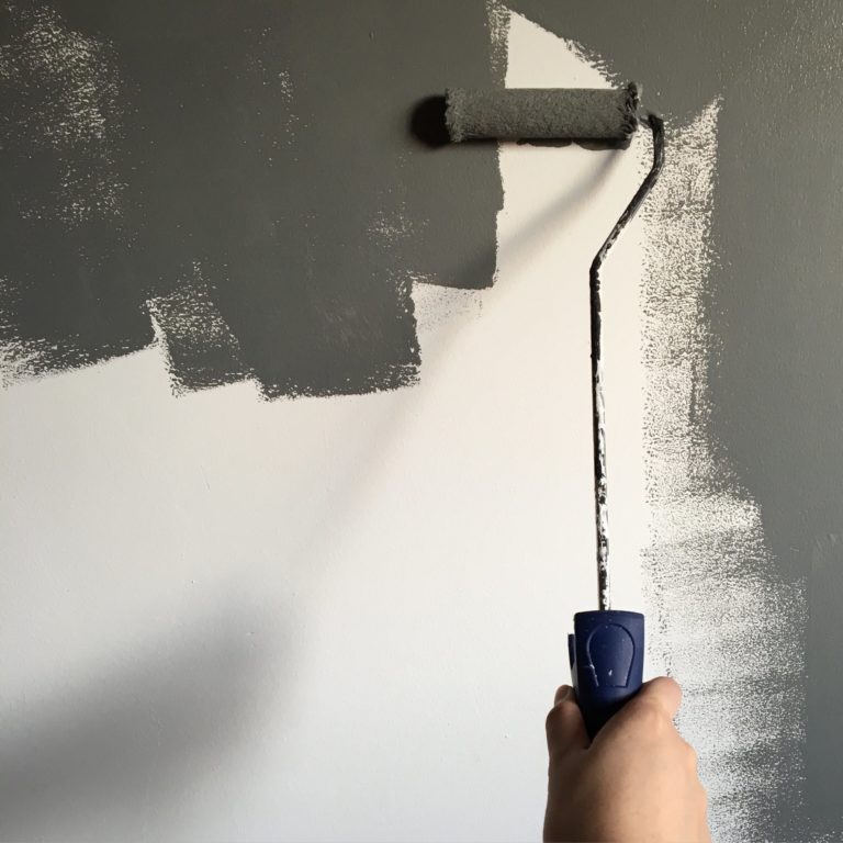 grijze verf roller op witte muur
